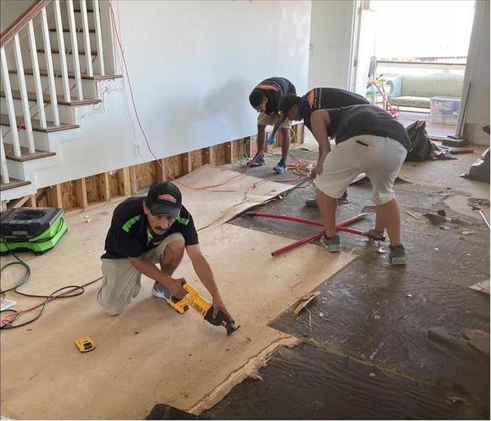Three technicians removing flooring